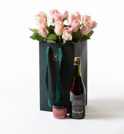 Rosa roser i gavepose med bobler og sjokolade